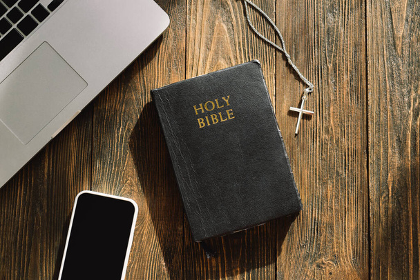 Kościół online niedziela nowa normalna koncepcja. Biblia, telefon komórkowy i słuchawki na drewnianym tle. - Zdjęcie, obraz