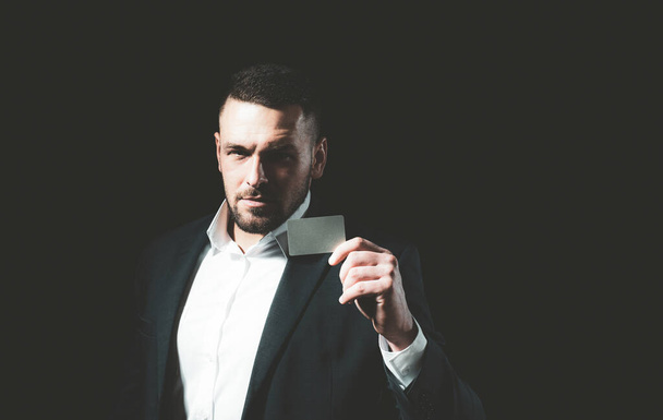 Handsome man in shirt and business suit holds a credit card. - Photo, Image