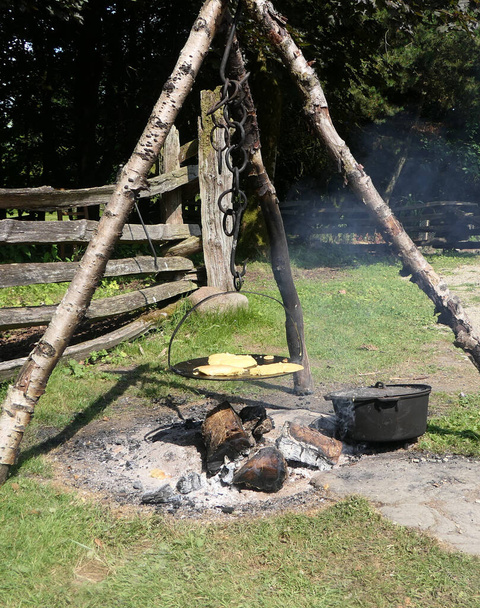 Hornear pan en una plancha sobre un fuego al aire libre en América de 1800 en el Ulster America Folk Park en Irlanda del Norte - Foto, Imagen