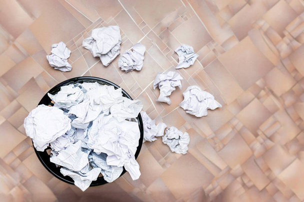 A trash can filled with crumpled papers stands on a wooden floor. view from above.paper recycling and reuse. concept idea development. lack of inspiration. - Foto, Imagem