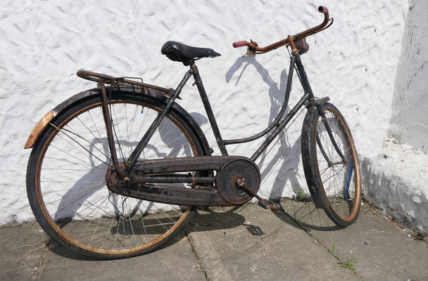 Παλιό ποδήλατο αντίκα κάθεται επάνω ενάντια σε ένα ιρλανδικό εξοχικό σπίτι  - Φωτογραφία, εικόνα
