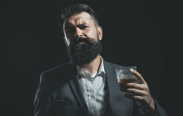 Fashion style concept. Tasting and degustation concept. Barman or Bartender serves cognac. Bearded handsome man holding glass of whiskey. - 写真・画像