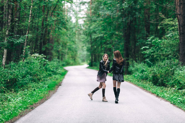 Дві дівчини, блондинка і брюнетка на дорозі в літньому лісі. Високоякісна фотографія
 - Фото, зображення