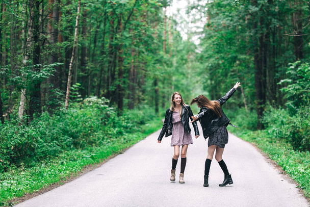 Две девушки, блондинка и брюнетка на дороге в летнем лесу. Высокое качество фото - Фото, изображение