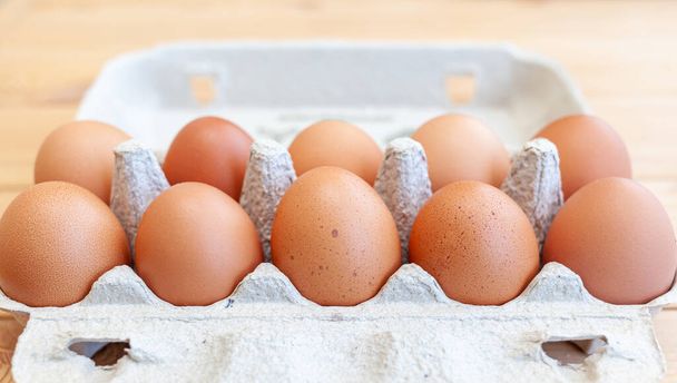 Ein paar braune Eier zwischen den Zellen eines großen Pappbeutels, ein Hühnerei als wertvolles Nährprodukt, ein Tablett zum Tragen und Aufbewahren empfindlicher Eier. Ein ganzes Paket Eier, ein wichtiges Nahrungsmittel - Foto, Bild