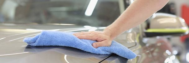 Male hand wiping hood of car with microfiber cloth closeup - Fotografie, Obrázek