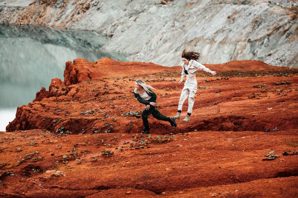 Girls in a post-apocalyptic place, a quarry with red earth and stones in work clothes. High quality photo - Photo, Image