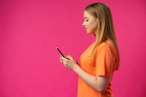Portrait of a young woman using mobile phone over color background. - Zdjęcie, obraz