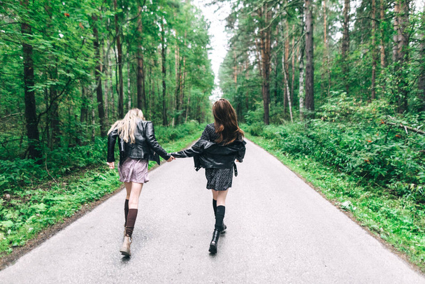 Дві дівчини, блондинка і брюнетка на дорозі в літньому лісі. Високоякісна фотографія
 - Фото, зображення