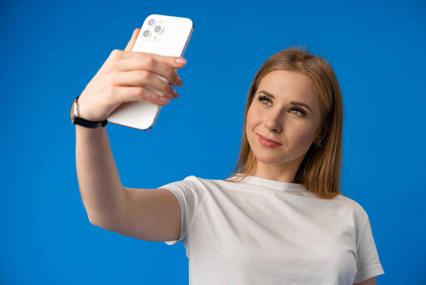 Happy woman taking selfie against studio color background - Fotó, kép