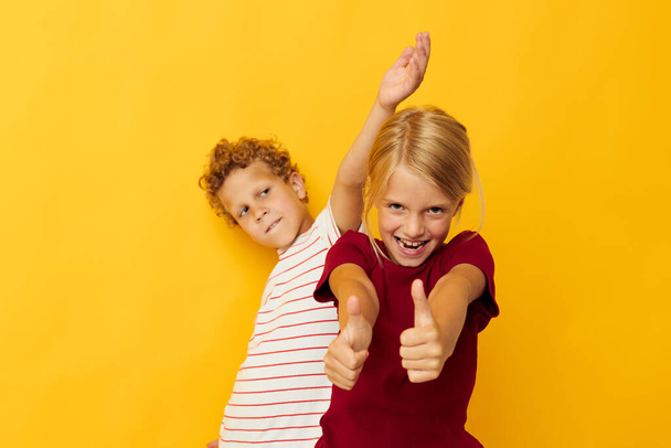 two joyful children cuddling fashion childhood entertainment yellow background - Foto, Imagen