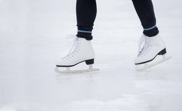 Ein Mädchen in schwarzen Hosen läuft tagsüber auf dem Eis des Stadions Schlittschuh - Foto, Bild