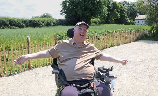 Usuario de silla de ruedas sentado al sol con los brazos extendidos - Foto, imagen