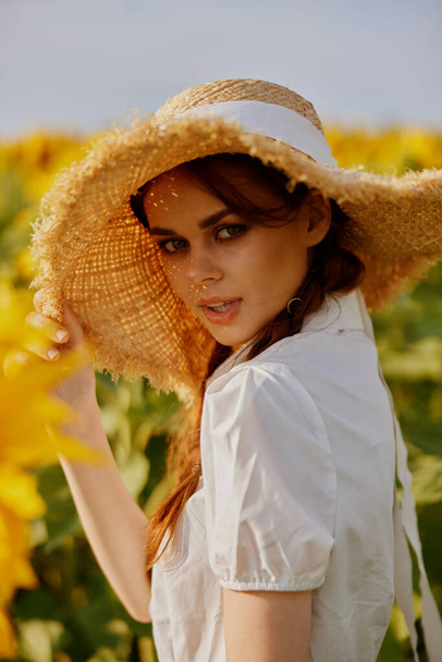 beautiful sweet girl in a hat on a field of sunflowers landscape - Foto, afbeelding