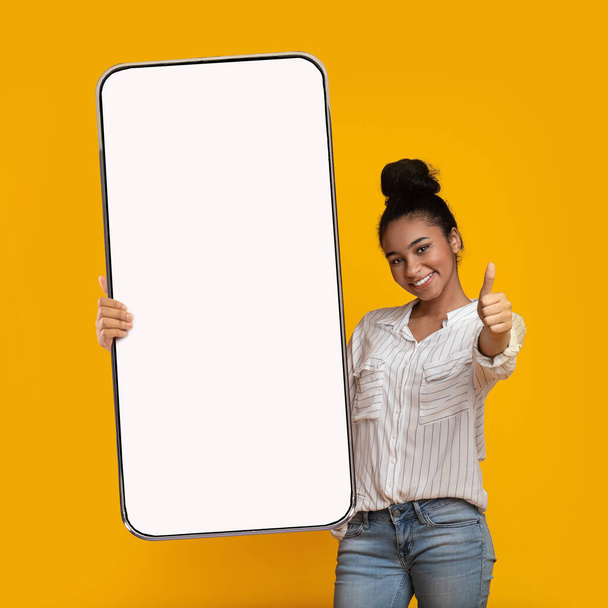 Чорна дівчина показує великий білий порожній екран смартфона і любить
 - Фото, зображення