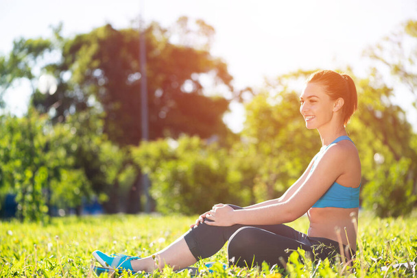 Beautiful smiling girl in sportswear relax in park - Photo, Image