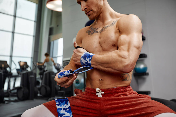 Young sporty handsome man wraps his arms with gymnastic bandage getting ready for barbell exercises. - Fotoğraf, Görsel