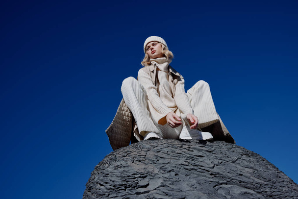 秋の服を着た若い女性が岩の風景の上に立つ青い空のライフスタイル - 写真・画像