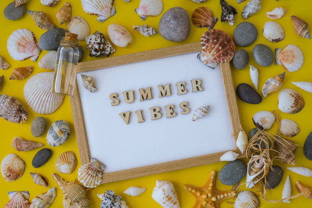 Composition sheet white paper text SUMMER VIBES, seashells, pebbles, mockup on yellow background. Blank, top view, still life, flat lay. sea vacation travel concept tourism and resorts. Summer holidays - Foto, imagen