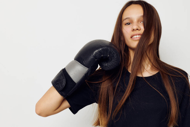 young beautiful woman in black sports uniform boxing gloves posing isolated background - Photo, image