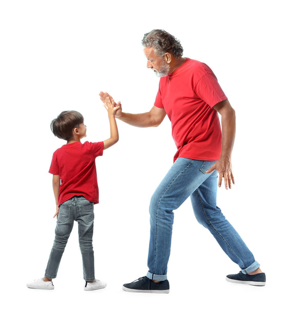 Little boy giving high-five to his grandfather on white background - Fotó, kép