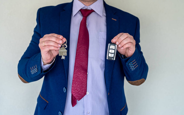продавец держит дома и ключи от машины, продажи или аренды концепции. покупка или подарок - Фото, изображение