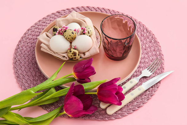 Schöne Tischdekoration für das Osterfest und Blumen auf rosa Hintergrund, Nahaufnahme - Foto, Bild