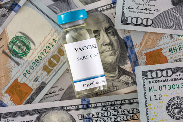 frascos de vacuna con jeringas se encuentran en billetes de dólar. Concepto de vacunación - Foto, imagen