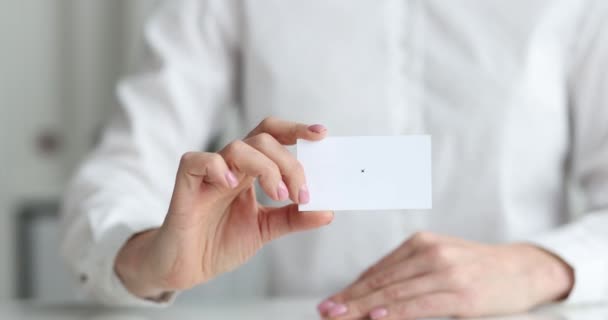 Menedzser nő ül az asztalnál, és tartja üres fehér névjegykártya a kezében közelkép 4k film - Felvétel, videó