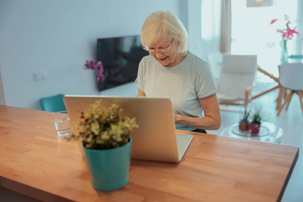 vanhempi nainen työskentelee kannettavan tietokoneen kanssa kotona - Valokuva, kuva