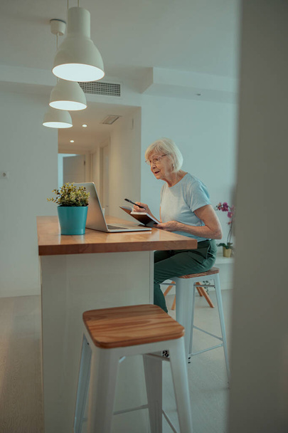 Starší žena sedící doma u stolu - Fotografie, Obrázek