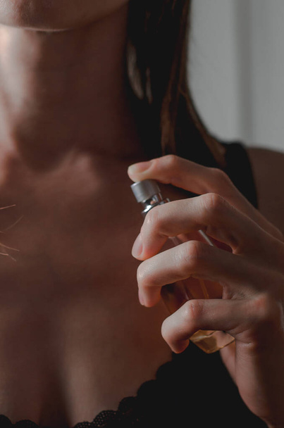 Parfüm in weiblichen Händen. Schöne junge Frau mit einer Flasche Parfüm in der Hand. - Foto, Bild