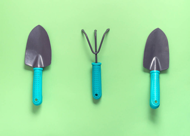 Garden tools rake shovel on a green background. The concept of spring planting. - 写真・画像