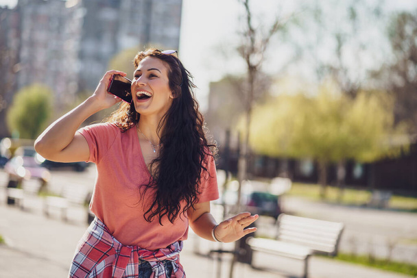 Happy young woman is enjoying sunny day outdoor in city. - Fotoğraf, Görsel