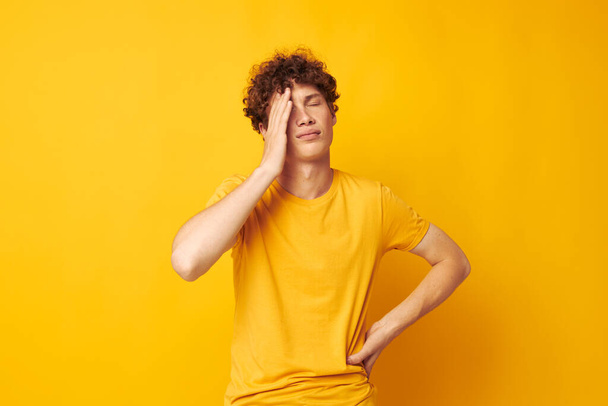 Young curly-haired man yellow t-shirt fashion hand gestures isolated background unaltered - Foto, Imagen