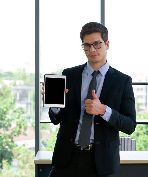 Empresários de ternos e gravatas levantar polegares para cima enquanto segurando computador tablet tela em branco. Ambiente de trabalho da manhã em um escritório moderno. - Foto, Imagem