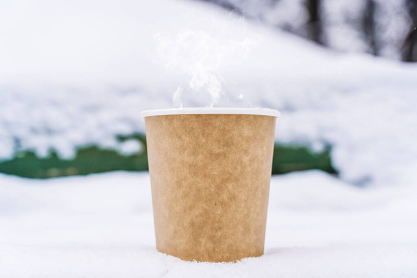 Coffee in a paper cup on a snowy winter background. Hot drink in cold weather. - Fotografie, Obrázek