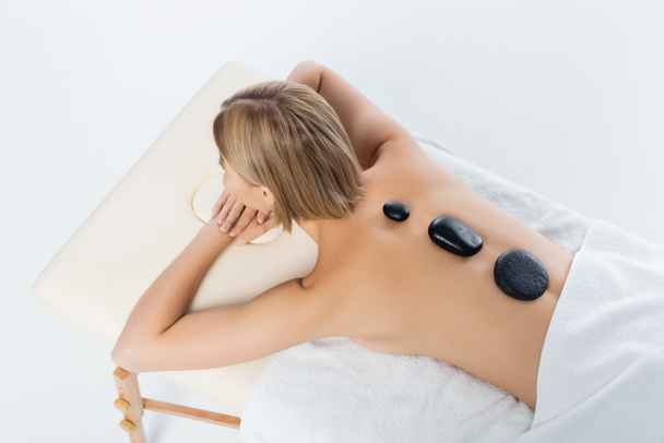 Hochwinkel-Ansicht der jungen Frau erhalten Hot-Stone-Massage isoliert auf weiß - Foto, Bild