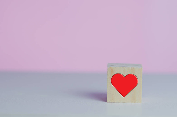 Cubos de madeira com símbolo de amor coração vermelho no fundo rosa e espaço de cópia. - Foto, Imagem