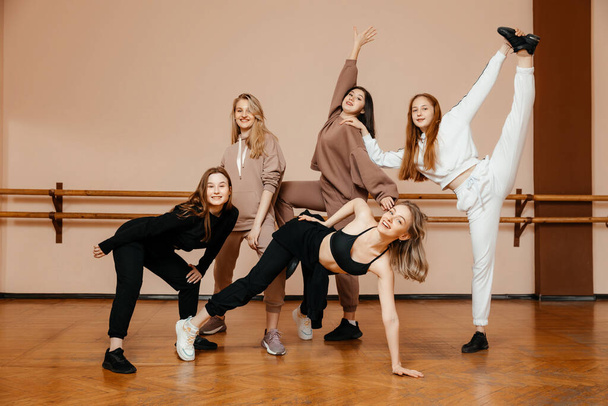 Mädchengruppe in Sportbekleidung, die Elemente des House Dance in einem Tanzstudio aufführt und mit Vergnügen tanzt. Das Konzept der Sportjugend.  - Foto, Bild