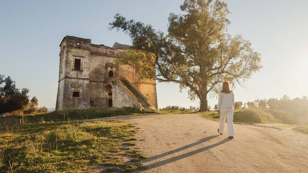 Beautiful girl in white dress enters an ancient castle in the countryside  - Φωτογραφία, εικόνα