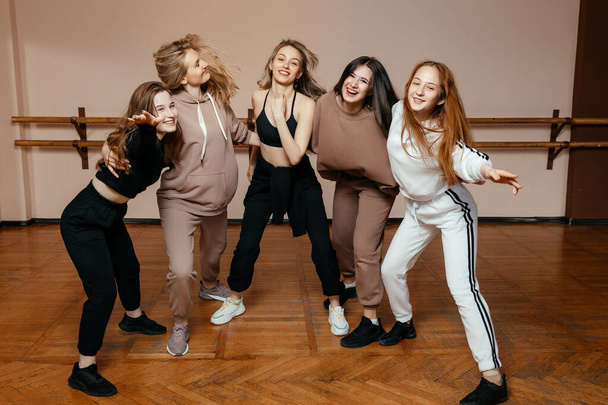 Groupe de filles en vêtements de sport, exécutant des éléments de danse maison dans un studio de danse, dansant avec plaisir. concept de jeunesse sportive.  - Photo, image