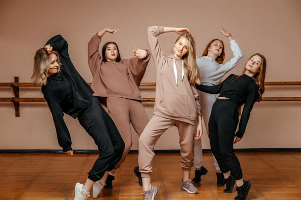 Group of girls in sportswear, performing elements of house dance in a dance studio, dancing with pleasure. The concept of sports youth.  - Foto, Imagen