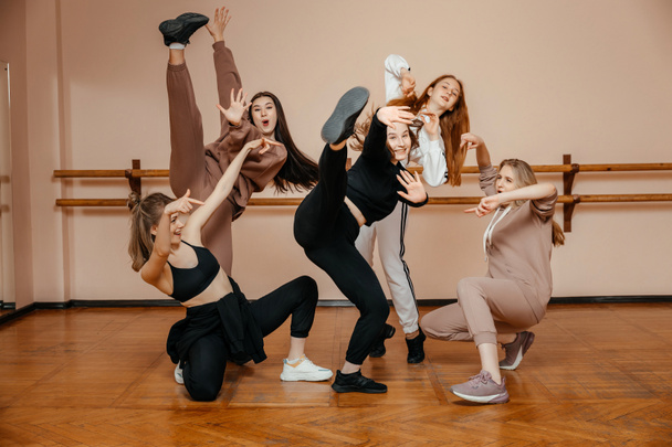 Ομάδα κοριτσιών σε αθλητικά είδη, ερμηνεύοντας στοιχεία του χορού σε ένα στούντιο χορού, χορεύοντας με ευχαρίστηση. Η έννοια της αθλητικής νεολαίας. - Φωτογραφία, εικόνα