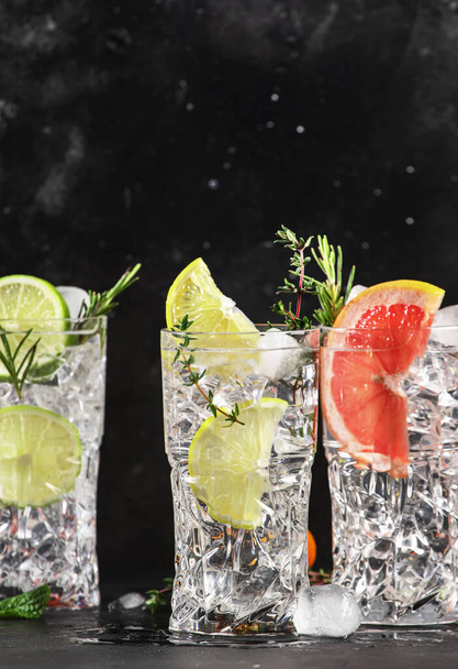 Gin tonic and citrus cocktails set. Alcoholic drinks with lime, lemon, grapefruit, orange, soda and herbs in highball glasses, black bar counter background. Summer cocktail party - Φωτογραφία, εικόνα