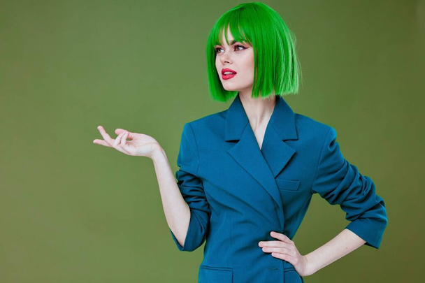Kaunis nuori nainen houkutteleva näyttää vihreä peruukki sininen takki aiheuttaa väri tausta muuttamaton - Valokuva, kuva