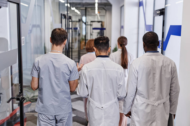 Visão traseira de vários jovens trabalhadores médicos em jalecos e uniforme - Foto, Imagem