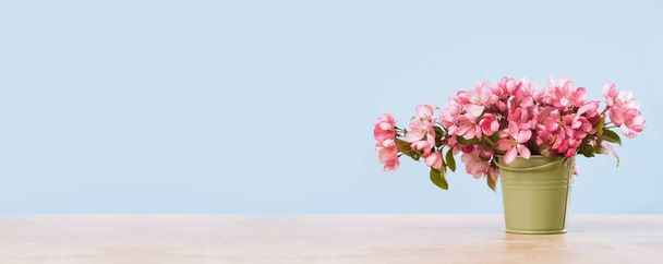 Rózsaszín tavaszi virágok egy apró olajbogyó vödörben - Fotó, kép