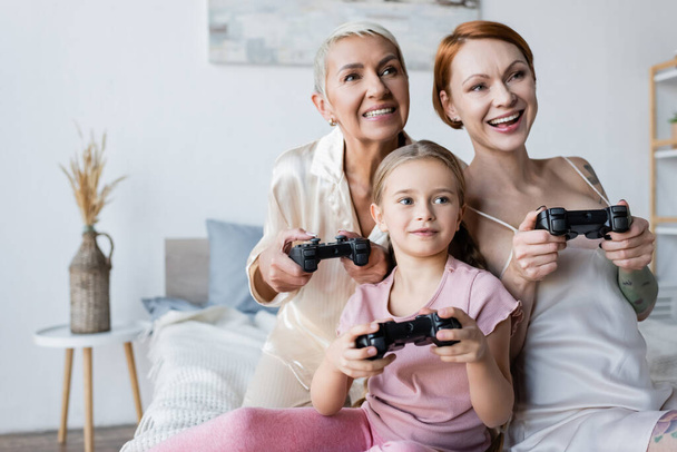 KYIV, UKRAINE - DECEMBER 8, 2021: Kid playing video game with mothers in bedroom  - Fotoğraf, Görsel