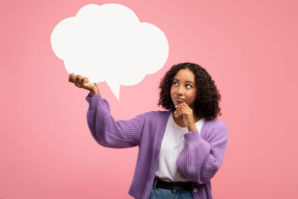 Millennial mulher negra segurando bolha de fala vazia no fundo do estúdio rosa, mockup. Notícias, diálogo, anúncio - Foto, Imagem